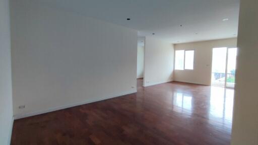 Spacious and well-lit empty living room with hardwood floors and balcony access