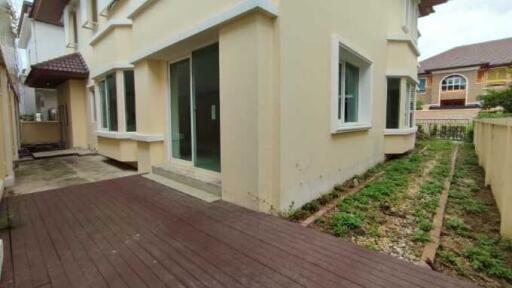 View of house exterior showing back yard with garden beds and a brick footpath