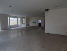 Spacious unfurnished living area with marble flooring and multiple windows