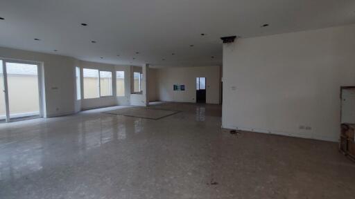 Spacious unfurnished living area with marble flooring and multiple windows