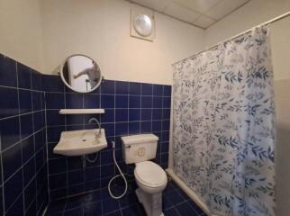 Compact bathroom with blue tiles showcasing a sink, toilet, and shower area