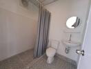 Compact bathroom with tiled floor, white toilet, pedestal sink, mirror, and shower curtain