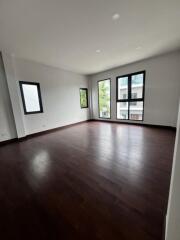 Spacious and empty living room with large windows and hardwood floors