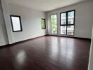 Spacious and empty living room with large windows and hardwood floors