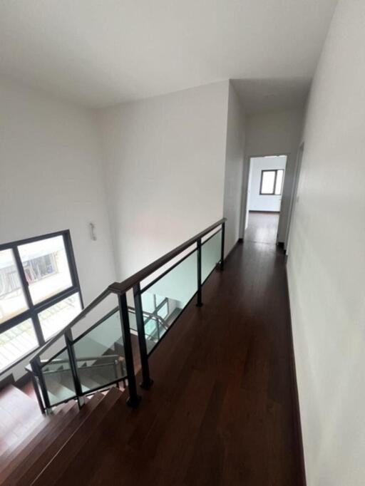 Bright and spacious upper-level hallway with hardwood floors and modern railing