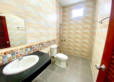 Modern tiled bathroom with sink, toilet, and ample lighting