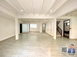 Spacious unfurnished interior of a bright living space with white beams and wooden flooring