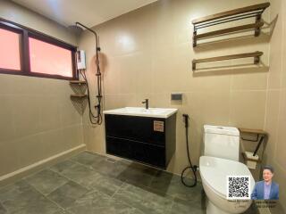 Modern bathroom with a walk-in shower, wall-mounted sink, toilet, and towel racks