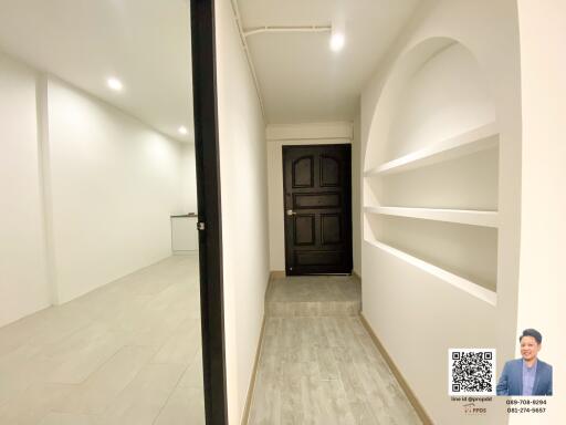 Spacious hallway leading to a wooden front door with built-in shelves on one side