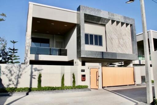 Modern two-story house with balconies and a wooden gate