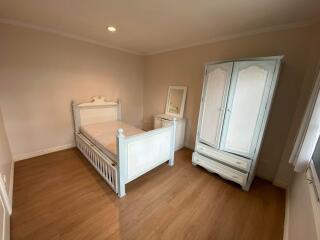 Spacious bedroom with wooden flooring and white furniture