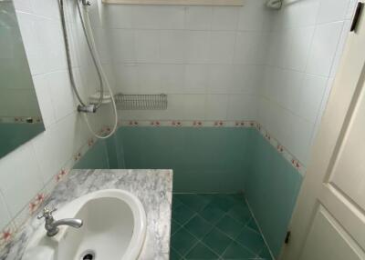 Compact bathroom with corner shower, sink, and teal tiles