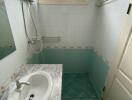 Compact bathroom with corner shower, sink, and teal tiles