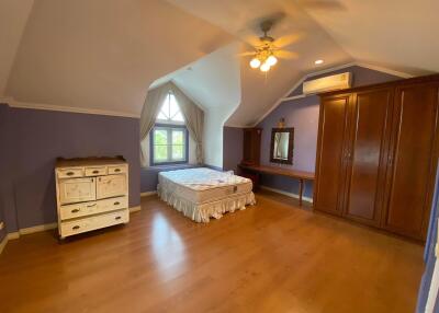 Spacious bedroom with wooden floors, large windows, and vaulted ceiling