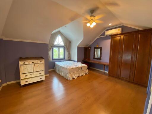 Spacious bedroom with wooden floors, large windows, and vaulted ceiling