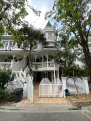 Victorian style house with multiple balconies and lush trees