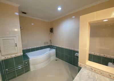 Spacious bathroom with corner bathtub and tiled walls