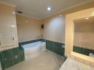 Spacious bathroom with corner bathtub and tiled walls