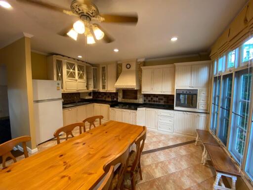 Spacious kitchen with wooden dining table, white cabinets, and modern appliances