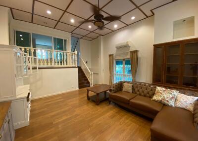 Spacious living room with high ceiling, hardwood floors and staircase