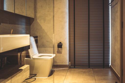 Modern bathroom with sleek design, featuring a wall-mounted toilet, large basin, and wooden accents