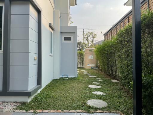 Side yard of a modern home with stepping stones and a water tank