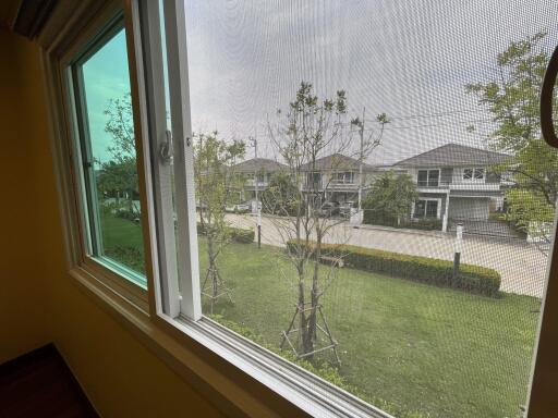 Bright bedroom with a large window overlooking green lawn and neighboring houses