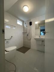 Modern tiled bathroom with walk-in shower, pedestal sink, and large mirror