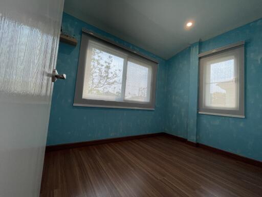Empty bedroom with blue wallpaper and wooden flooring