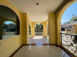 Spacious covered front porch of a residential building with tiled flooring and view to the yard