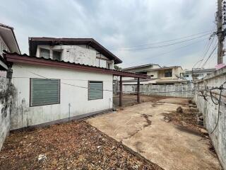 Exterior view of a house with a spacious empty lot and metal roof carport