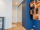 Modern entryway with blue accent wall, built-in shelves, and mirrored closet doors