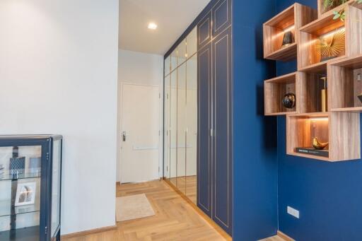 Modern entryway with blue accent wall, built-in shelves, and mirrored closet doors