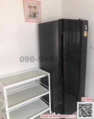 Compact kitchen with large black refrigerator and metal shelving unit