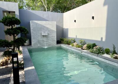 Elegant outdoor swimming pool with waterfall feature and landscaped surroundings
