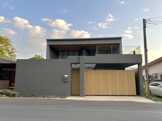 Modern two-story house with large windows and a wood-finished gate