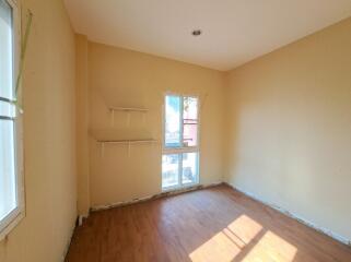 Bright empty bedroom with hardwood floors and a large window