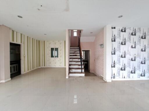 Spacious unfurnished living room with staircase and patterned wallpaper