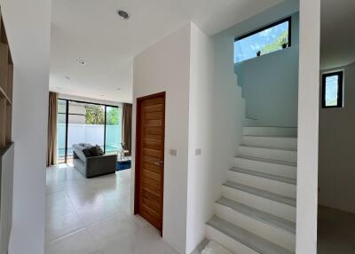 Modern home interior with open plan living space, staircase, and entrance