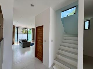 Modern home interior with open plan living space, staircase, and entrance