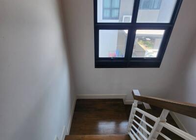 Staircase area with high window and wooden flooring