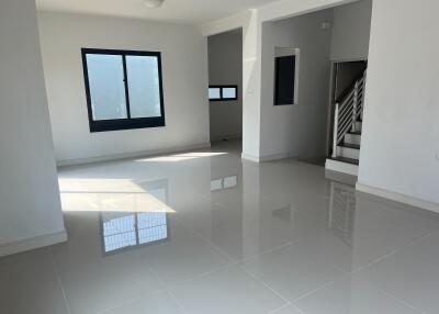 Spacious and well-lit empty living area with glossy floor tiles and a staircase