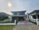 Modern two-story house with a spacious front yard and a 'For Sale' sign