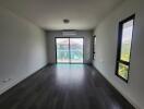 Spacious and well-lit empty living room with large windows and balcony access