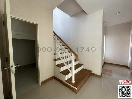 Interior view of a staircase area with white walls and wooden steps