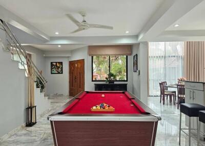 Spacious living area with pool table, dining space, and elegant staircase