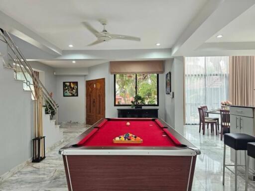 Spacious living area with pool table, dining space, and elegant staircase