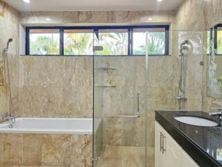 Modern bathroom with natural stone tiles, glass shower, and bathtub