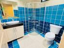 Bright bathroom with blue tiles, glass shower, and modern fixtures