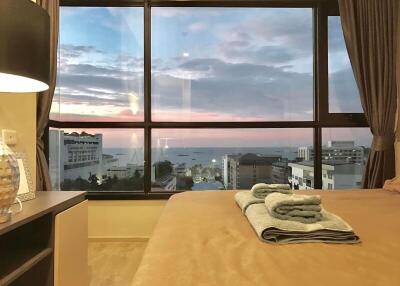 Cozy bedroom with a scenic sunset view through large windows
